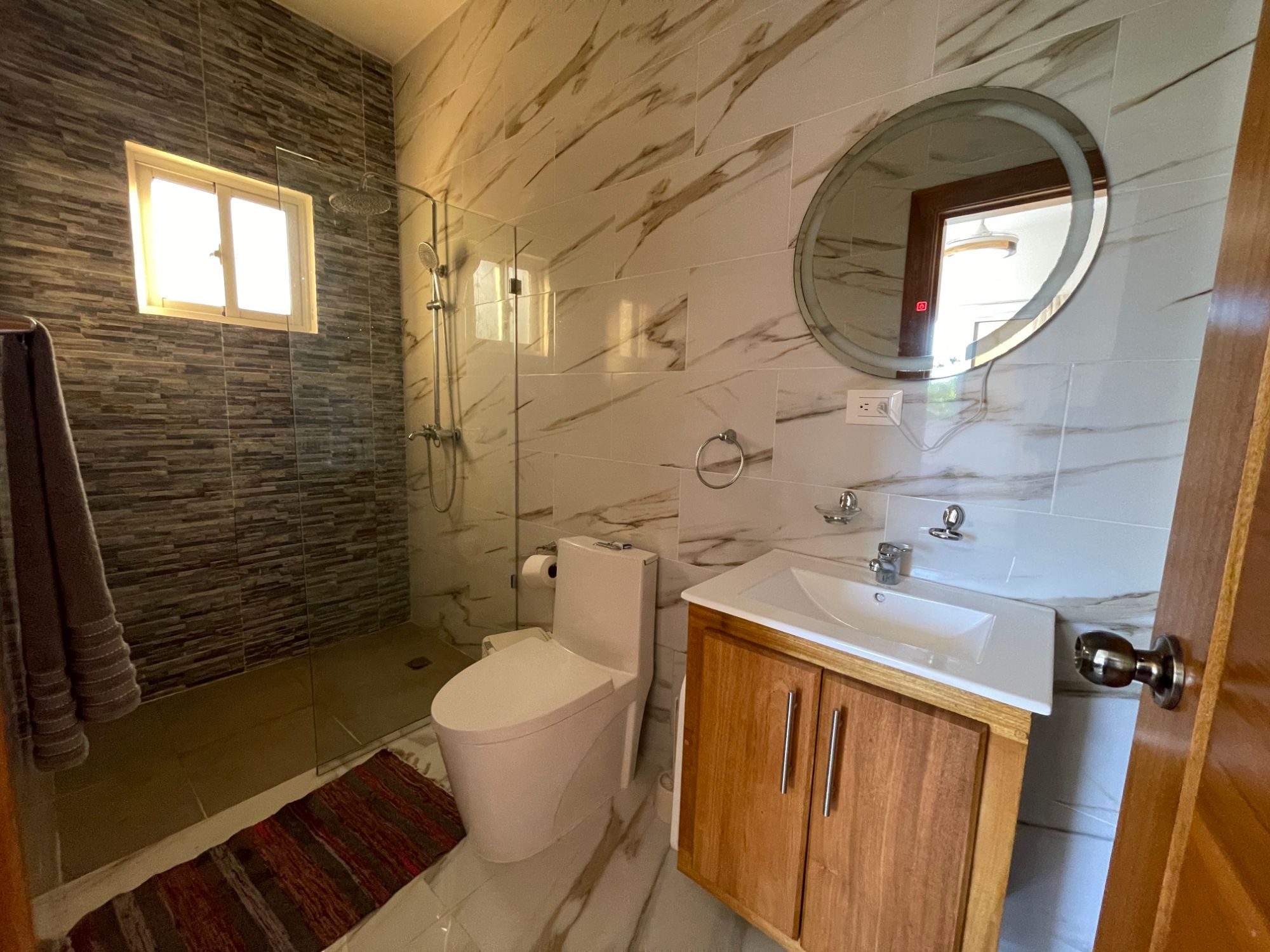 A bathroom with a stone feature wall and a walk-in shower