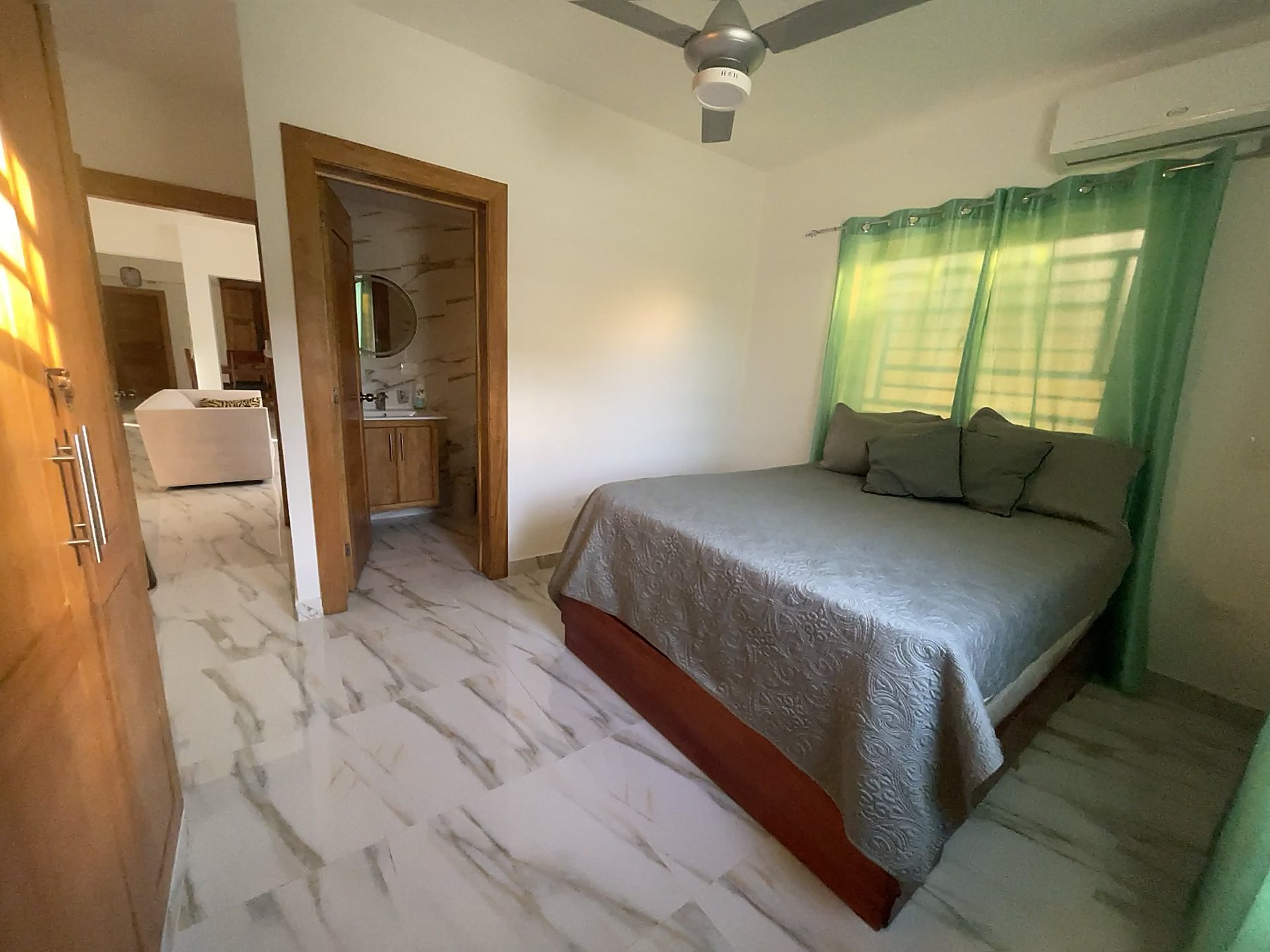 A bedroom with a ceiling fan, air conditioning and its own bathroom