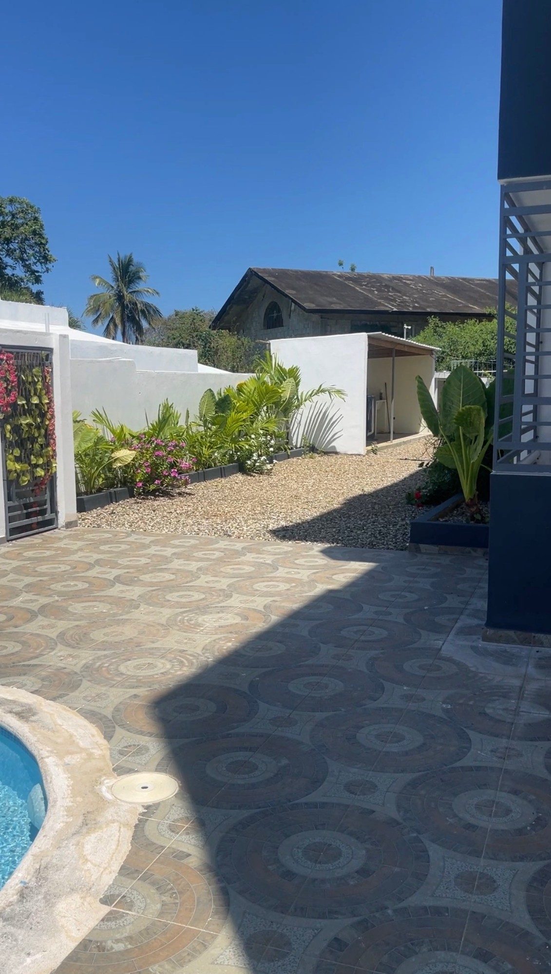 The tiled patio and the planted garden beside the pool